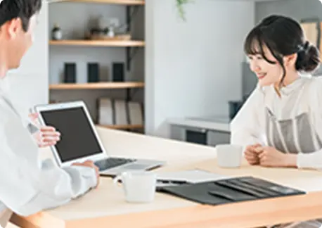 車の周りに立ち、車の外装を確認しながら説明をしている男性と、それを聞いている人物。背景には高級車が並んでいる。